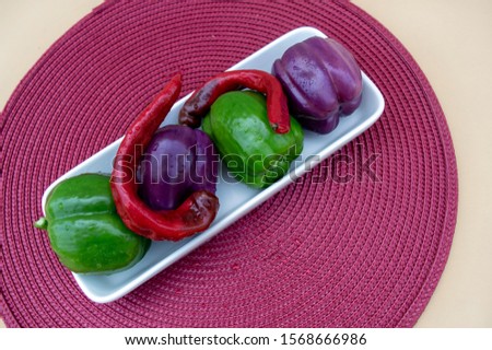 Colorful peppers make a pretty display with water droplets, a white platter and pretty placemat composed with a nice bokeh effect.