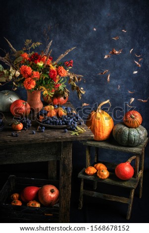 
Autumn composition with flowers and pumpkins. Old furniture gives the picture a special style.