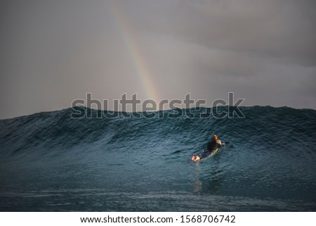 Young surfer surfing under a colourful rainbow, Bronte Beach Australia