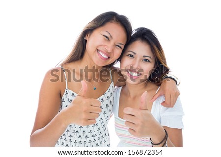 Two smiling asian women giving thumbs up on white background
