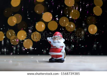 Santa doll on a black background with golden bokeh, happy new year, merry christmas