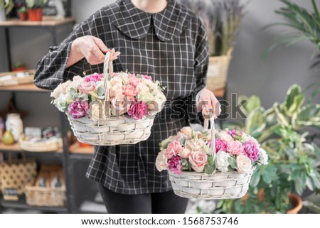Two Flowers arrangements in Wicker basket. Modern floral shop. Finished work of the florist. Cute bouquet of mixed flowers in womans hands. Delivery fresh cut flower from online store