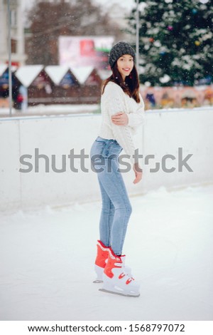 Girl in a winter city. Beautiful lady in a white sweater. Woman in a ice arena