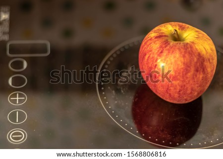 The picture of an apple placed on an electric stove