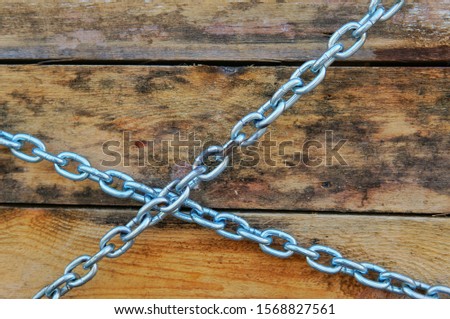 A metal chain wraps around rough uncut wooden boards