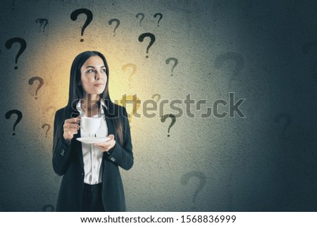 Young businesswoman with cofe cup on concrete wall background with question marks. Confusion and choice concept