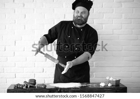 Bearded chef chef prepares meals at the table in the kitchen
