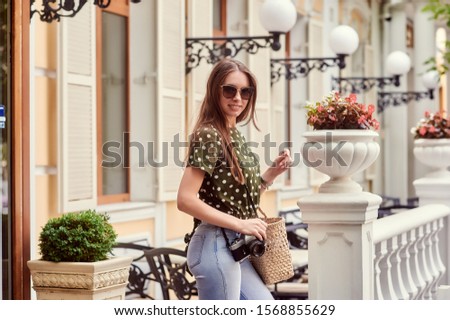 Young beautiful woman with camera on a walk in the city