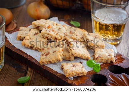 Cracker cookies with fried onions on a wooden board with a glass of beer, horizontal