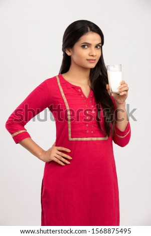 Indian young woman holding glass of milk on white.