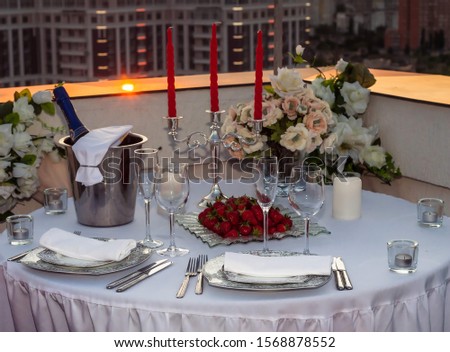 romantic table with candles and strawberries in a restaurant at sunset