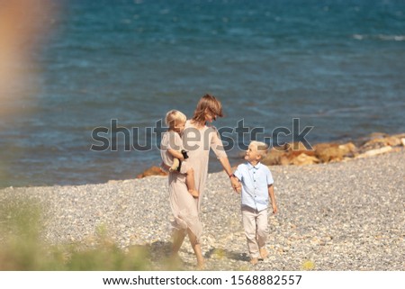 Pretty happy mom and little children on a walk near the sea
