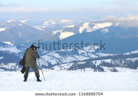 The photographer takes pictures from the top of a snowy mountain. Photo of a winter landscape and coniferous trees covered with snow
