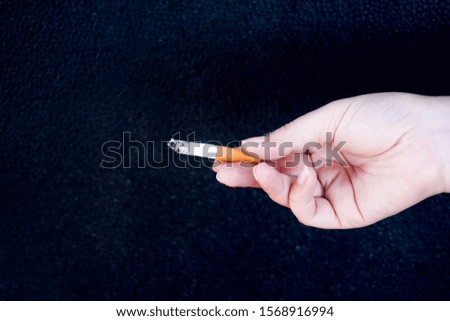 Hand is holding a cigarette on black background,No smoking. Quitting from addiction concept.