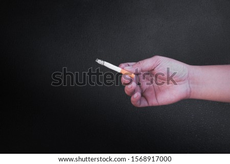Hand is holding a cigarette on black background,No smoking. Quitting from addiction concept.