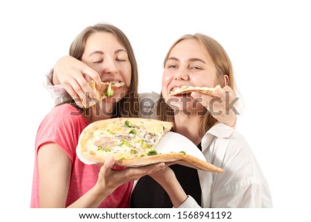 two girls eats pizza on white background, laughing