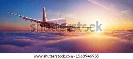 Passengers commercial airplane flying above clouds in sunset light. Concept of fast travel, holidays and business. Royalty-Free Stock Photo #1568946955