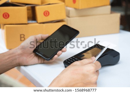businessman hand using the card machine to pay the goods before packing in the box to deliver to the customer