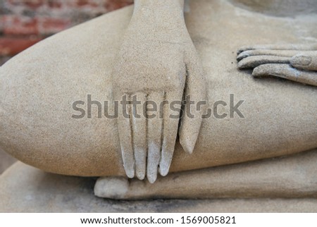 A hand on a stone Buddha statue.           