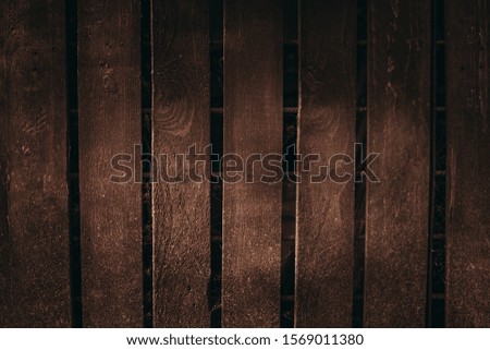 Photo of vintage wooden board with rough texture with empty space for your text or image. Illuminated dark brown wooden wall (background) - natural and soft light in the middle.  The old surface.