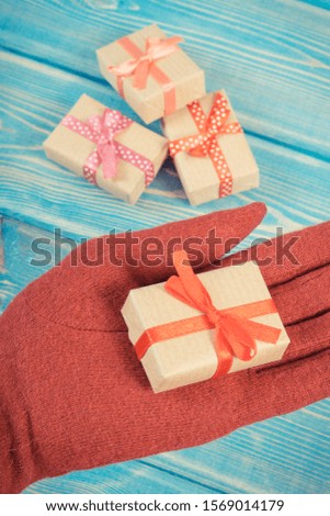 Vintage photo, Hand of woman in red woolen gloves and wrapped gifts for Christmas, Valentine, birthday or other celebration