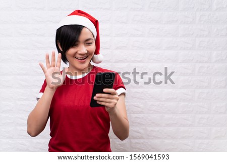 Happy woman woman wearing santa hat and use smart phone