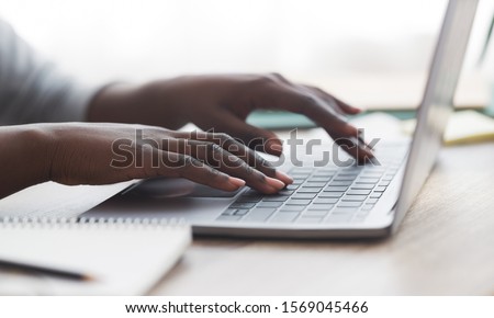 Closeup of unrecognizable afro woman typing on laptop keyboard while working in office, panorama Royalty-Free Stock Photo #1569045466