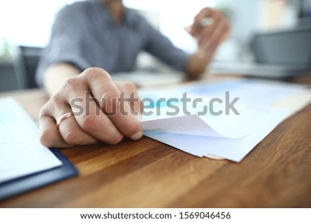 Close up of young businessman holding paper with financial information, editing documents, explaining marketing strategy or planning company economic growth at brainstorming meeting at office.