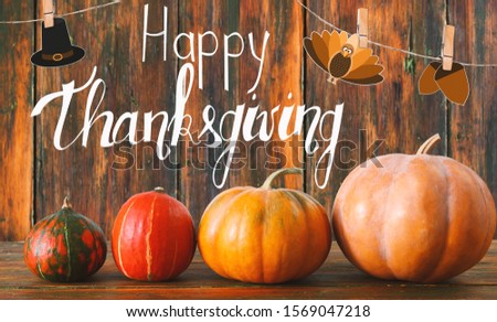 Happy thanksgiving greeting card with traditional pumpkins, wooden background