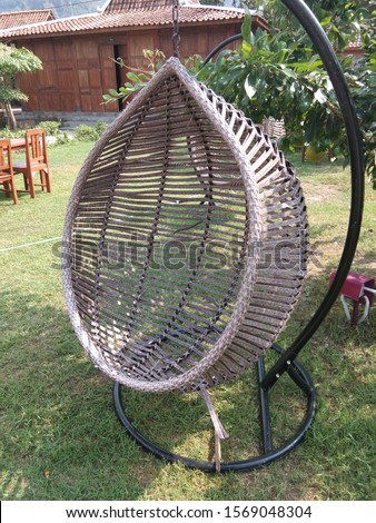 
swing chair in the garden with a half round shape from wicker