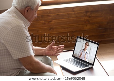 Focused older 80s male patient consulting with doctor via computer video call. Senior man looking at laptop screen, talking to therapist cardiologist online, older generation using modern technology. Royalty-Free Stock Photo #1569052048