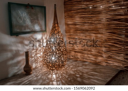 Corner of relaxation with a artisan lamp maded of naturals materials, in the botton the wooden little wall