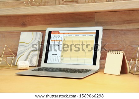 Modern laptop with calendar on screen in office