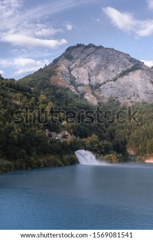 View of Mountains and Blue Lake with blue sky at "Lac de Chambon" barrage (Lake) in the French Alps in Isère, Ecrins National Park, France during summer road trip