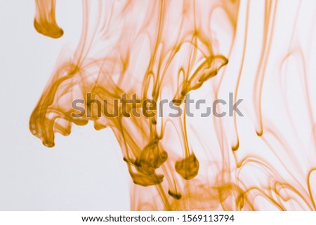 Yellow liquid in water making abstract forms