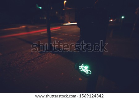intersection at night with traffic light for a cycling lane showing green bicycle symbol - blurred background with moving lights- urban commuting concept
