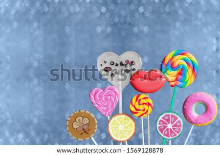 Colorful lollipops of different shapes and cookies in the form of lips, on a stick. Blue bokeh background