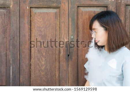 Portrait of fashion woman smoking while wearing glasses against wooden door
