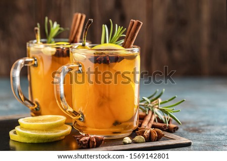 Hot drink cocktail for New Year, Christmas, winter or autumn holidays.
Toddy. Mulled pear cider or spiced tea or grog with lemon, pear, cinnamon, anise, cardamom, rosemary. Royalty-Free Stock Photo #1569142801