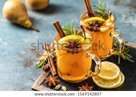 Hot drink cocktail for New Year, Christmas, winter or autumn holidays.
Toddy. Mulled pear cider or spiced tea or grog with lemon, pear, cinnamon, anise, cardamom, rosemary. Royalty-Free Stock Photo #1569142807