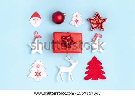 New Year and Christmas composition. Square frame from red balls, white stars, chrismas tree, deer and gift box on pastel blue paper background. Top view, flat lay Royalty-Free Stock Photo #1569167365