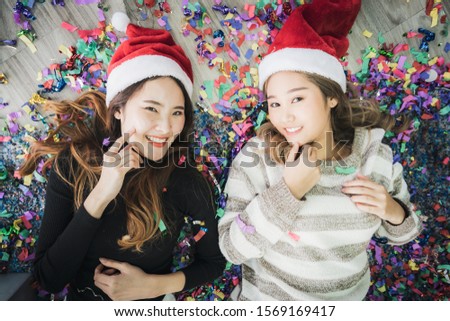 Celebration party group of Asian cheerful attractive young woman in Santa Claus hat with confetti on the floor, happy and funny concept. In 2020 New year holiday.