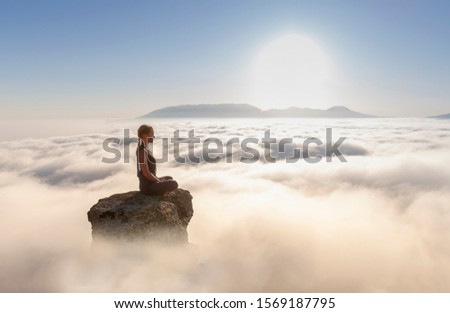 young beautiful cute blonde girl practices yoga on a rock on a background of the sea, asana lotus, healthy lifestyle concept