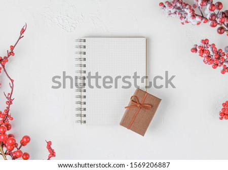 schoole notepad on white background with red berries and gifts, holiday concept flat lay. new goals, plans and to do list top view.