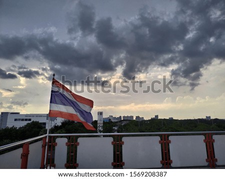 The Thai flag is flying and the sky is wide.