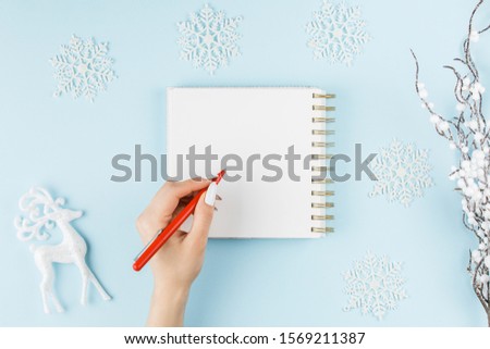 white notebook on a blue background with hand and gifts, holiday concept flat lay. new goals, plans and to do list top view.