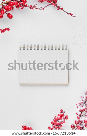 schoole notepad on white background with red berries and gifts, holiday concept flat lay. new goals, plans and to do list top view.