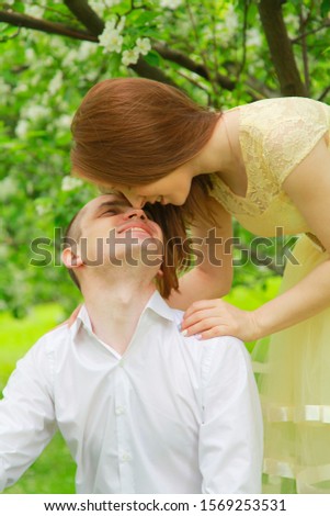 The bride and groom are walking in the apple orchard, posing under the branches of an apple-tree