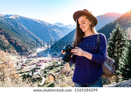 Stylish trendy hipster woman traveler photographer with camera in a felt hat during taking pictures of the mountains and uzungol lake in Trabzon during Turkey travel