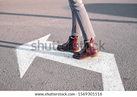 Feet walking along the left turn sign. Concept of making correct decisions, changing direction or attitude in life Royalty-Free Stock Photo #1569301516